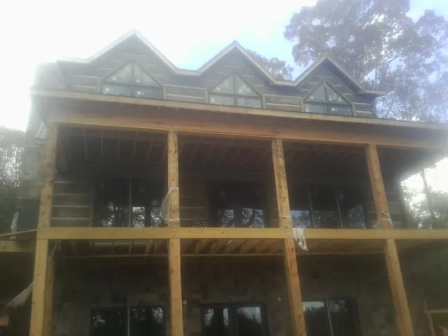 Dormers and porch framing on a large log home under construction — Roof Coating work by our crew in Bluefield