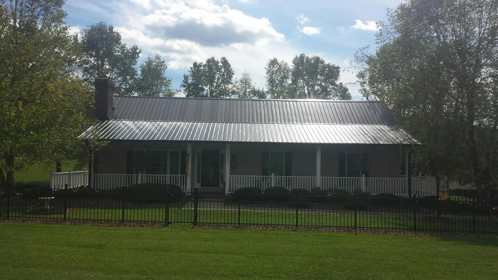 Gray metal roof on a brick ranch with a full width front porch — Gutter Guard Installation work by our crew in Bluefield