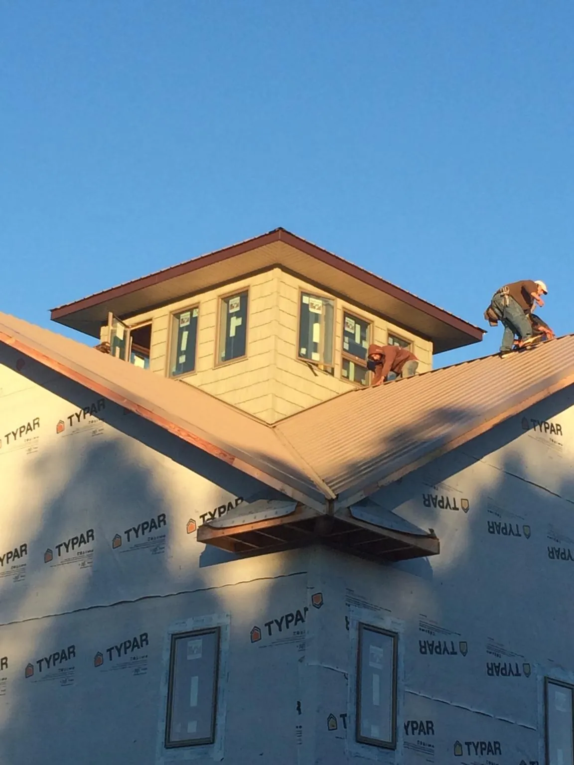 Roofers working around a rooftop cupola on a new metal roof at sunset — Roof Waterproofing in Bluefield by Roofing Brothers